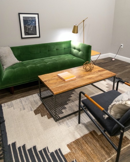 Modern living room with a patterned area rug and green sofa